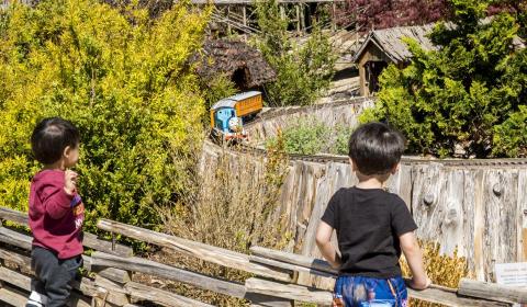 Two kids watch Thomas the Tank Engine moving down the track at the Kentucky Children's Garden